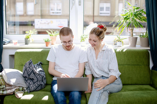 Zwei Studierende arbeiten am Laptop, auf einem Sofa sitzend.