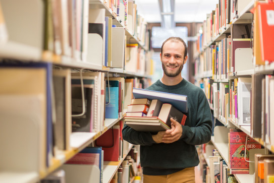 Student in a library A student in a library holding books in his hands