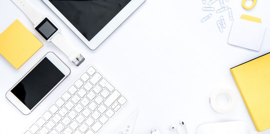 A tablet, a scissor, a smartphone, a notepad, a watch, a keyboard and a ruler are arranged on desk