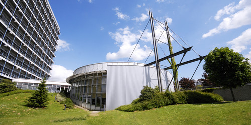 Panoramaaufnahme des Audimax und des Mathematik-Gebäudes mit blauem Himmel.