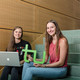 Zwei Studentinnen sitzen mit Laptop und TU-Logo auf einer Treppe.