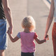 Familie_01 Erwachsene halten ein Kind rechts und links an den Händen.