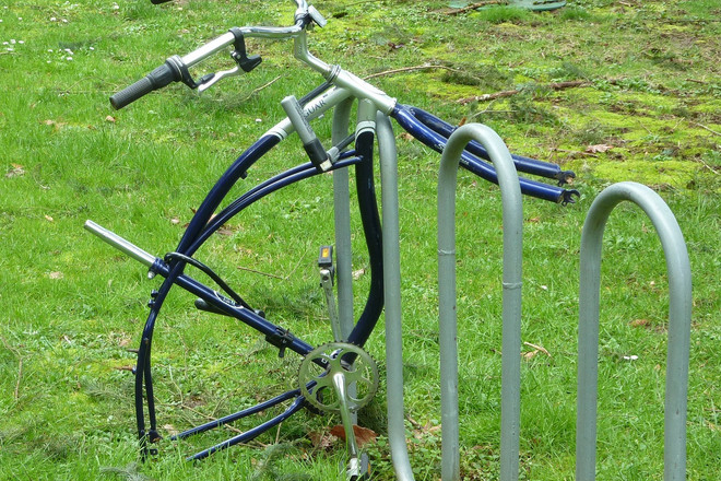 Ein gestohlenes Fahrrad mit nur einem Lenker ist auf grünem Rasen angeschlossen.