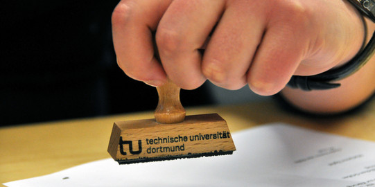 Recognition of Examinations close-up of a hand holding a stamp over a piece of paper