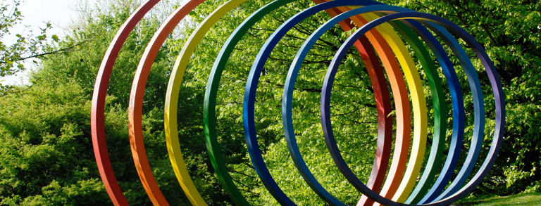 Spektralringe Große bunte Spektralringe aus Stahl stehen auf grünem Rasen.