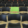 A green chair in the middle of black chairs