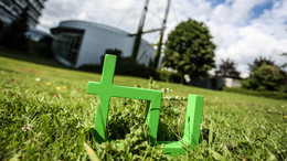 September Im Vordergrund steht das TU-Logo im Gras, im Hintergrund das Audimax.