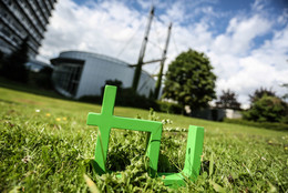 Oktober Im Vordergrund steht das TU-Logo im Gras, im Hintergrund das Audimax.