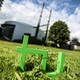 TU-Logo Im Vordergrund steht das TU-Logo im Gras, im Hintergrund das Audimax.