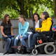 Studierende mit Behinderung Vier Studierende, darunter Studierende mit Behinderung, sitzen gemeinsam auf dem Campus.