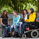 Studierende mit Behinderung Vier Studierende, darunter Studierende mit Behinderung, sitzen gemeinsam auf dem Campus.