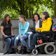 Studierende mit Behinderung Vier Studierende, darunter Studierende mit Behinderung, sitzen gemeinsam auf dem Campus.