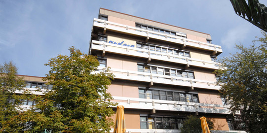 A building with plenty floors surrounded by trees.