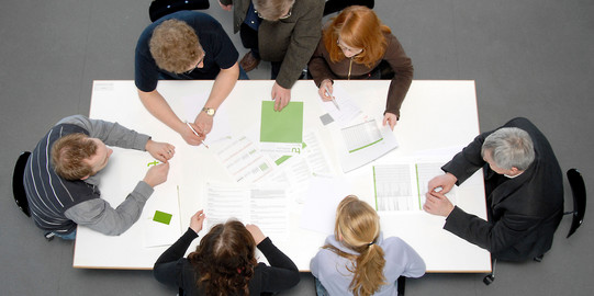 meeting situation with students and professors five students and a professor sitting aroung a table