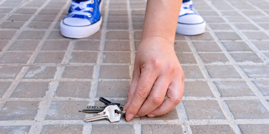 Key find Close-up of hands picking up a bunch of keys from the street.