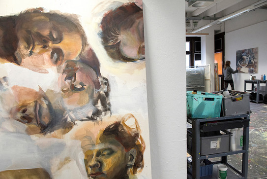 A painting of several faces in an atelier