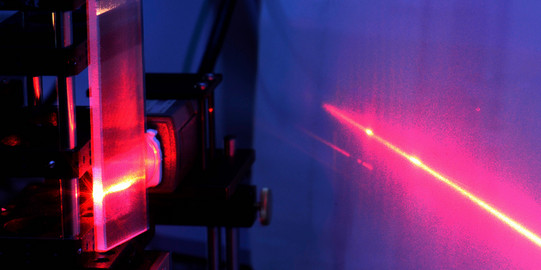 Eine Detailaufnahme eines Lasers im Labor in roten und blauen Farben.