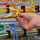 Verkabelung Sicherrungsraum Eine Hand prüft verschiedene Kabel in einem Sicherungsraum für Elektrik.