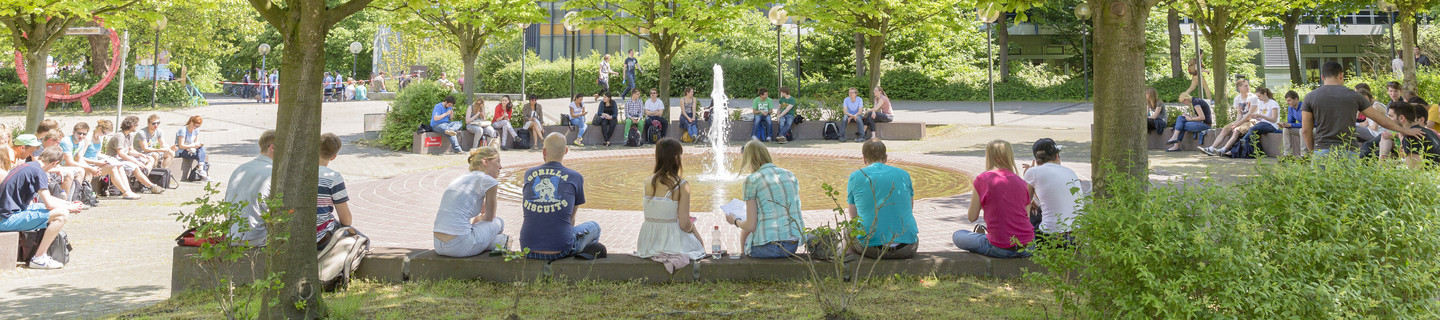 Students sitting next to the well on Campus North in the summer time