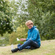 Student auf Wiese Ein Student sitzt auf einer Wiese und liest in einem Buch.