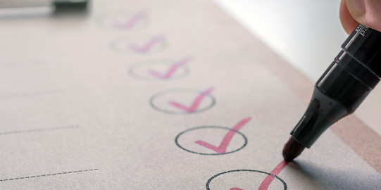 Checkliste eine Liste auf einem Klemmbrett, ein Stift hakt einzelne Felder ab