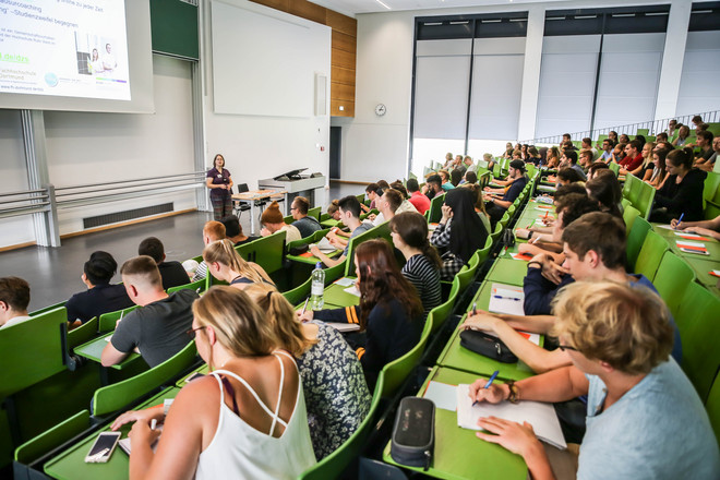Seminarraumgebäude, Vorlesung von der Seite Studierende sitzen im Seminarraumgebäude und schreiben mit.