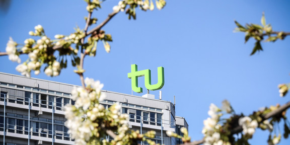 TU im Frühling_02 Das TU Gebäude umgeben von blühenden Kirschblüten.