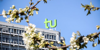 Das TU Gebäude umgeben von blühenden Kirschblüten.