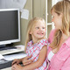 Mutter mit Tochter auf dem Schoß am PC Arbeitsplatz.