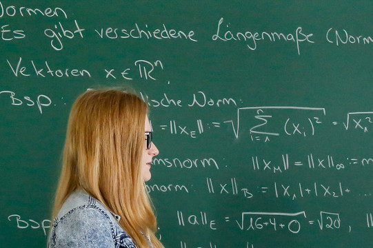 Two students standing in front of a blackboard