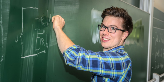 Student at the blackboard A student is writing on a chalk board.