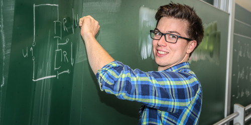 Ein Student schreibt eine mathematische Gleichung an eine Tafel