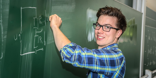A student is writing on a chalk board.