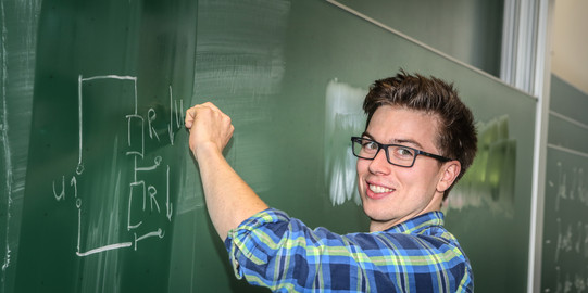Ein Student schreibt eine mathematische Gleichung an eine Tafel