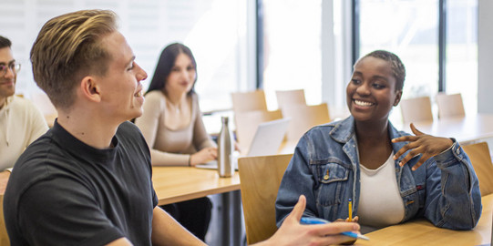 Students sit in the seminar room and talk to each other.