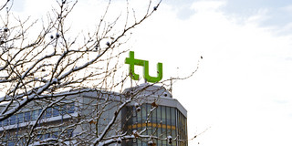 A building with TU Dortmund logo and branches covered with snow.
