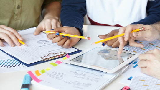 On a table are pads and sheets, a tray used by one hand.