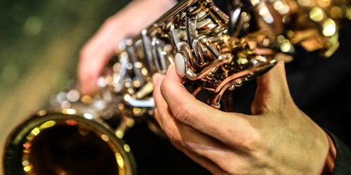 Zwei Hände spielen Saxophon.