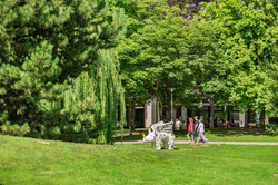 Studierende auf dem grünen Campus mit Nashornskulptur