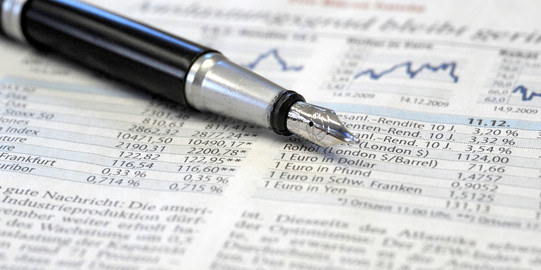 Eine Zeitung mit Informationen zur Börse und ein Füllfederhalter liegt darauf.