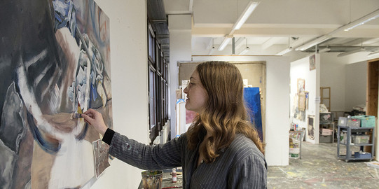 Eine Frau malt ein Bild in einem Atelier.