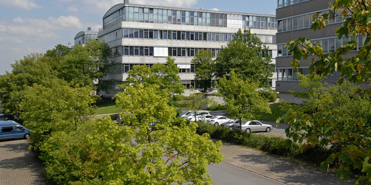 Geschossbauten am Campus Süd. Im Vordergrund grüne Laubbäume.