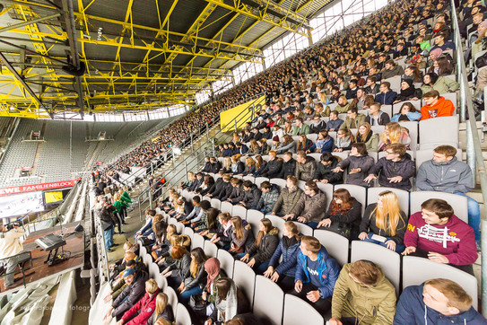 First semester students sit in the stands at the stadium during the welcoming of first-semester students and watch a show act sideways. 